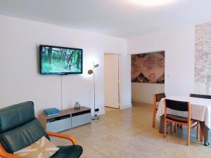 ein Wohnzimmer mit einem Tisch und einem TV an der Wand in der Unterkunft Le Pouy, Jardin, Terrasse & Stationnement in Saint-Vincent-de-Paul