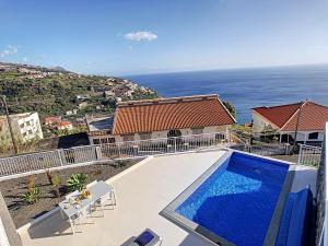 a house with a swimming pool in front of the ocean at Casa dos Amores by LovelyStay in Calheta