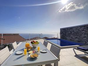 a table with food and drinks on a balcony with a pool at Casa dos Amores by LovelyStay in Calheta