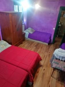 Habitación con 2 camas, paredes de color púrpura y suelo de madera. en Hostería Casa Flor, en Murias de Rechivaldo