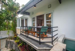 un porche con sillas verdes y una mesa en Casa Priya Ubud, en Ubud