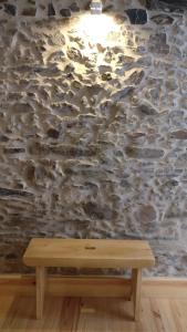 um banco de madeira em frente a uma parede de pedra em Casinhas de S. Francisco T2 Azeitona by LovelyStay em Freixo de Espada à Cinta