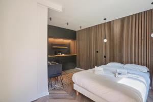 ein Schlafzimmer mit einem weißen Bett und einer Holzwand in der Unterkunft Studio in Neuilly Porte Maillot by Studio prestige in Neuilly-sur-Seine