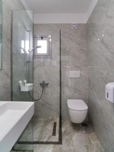 a bathroom with a shower and a toilet and a sink at Vironas Hotel in Himare
