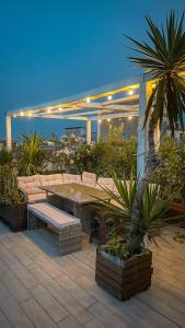 a patio with a table and benches and plants at Follow The Sun Catania - Rooftop Terrace in Catania