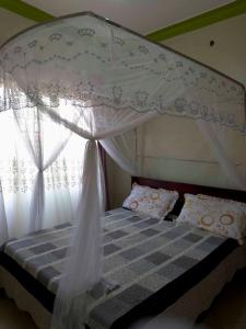 a bedroom with a bed with a canopy and a window at Olive Palm Suites Jinja in Jinja