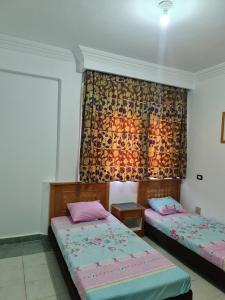 two beds in a room with a curtain and sidx sidx sidx at Amazing flat in Gardenia plaza in Sharm El Sheikh