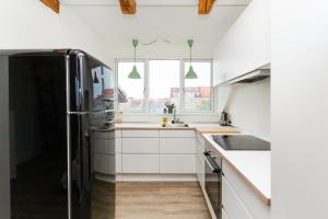 kuchnia z białymi szafkami i czarną lodówką w obiekcie Come Stay in Penthouse With Room For 2-People w mieście Aarhus