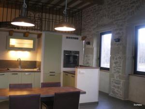 a kitchen with a wooden table and a refrigerator at Petit Gite De La Renaissante in Peyrins