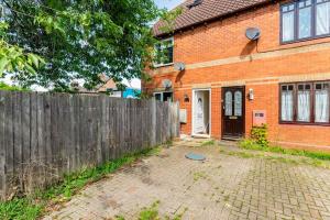 a brick house with a wooden fence in front of it at Charming Entire 2-Bedroom House in Milton Keynes in Milton Keynes