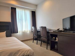 a hotel room with a bed and a desk with a television at Platon Hotel Yokkaichi in Yokkaichi