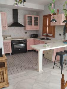 Lecrin的住宿－Casa El Naranjo Azul Granada，厨房配有粉红色橱柜和白色桌子
