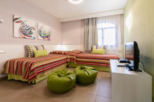 a hotel room with two beds and a desk at HD Parque Cristobal Tenerife in Playa de las Americas