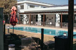 a pool with a red umbrella and chairs and a building at Sizakele Stays in Johannesburg