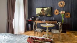 ローマにあるQT Suites Romaのテーブル、椅子、テレビが備わる客室です。