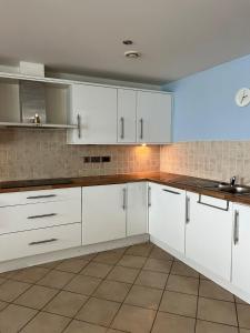 a kitchen with white cabinets and a tile wall at Doc Fictoria in Caernarfon