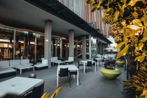 un restaurant avec des tables blanches, des chaises et des plantes dans l'établissement Mod 05 Bike Hotel, à Castelnuovo del Garda