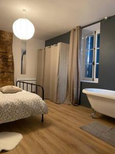 łazienka z wanną, łóżkiem i oknem w obiekcie La Maison des Pressoirs w mieście Sancerre