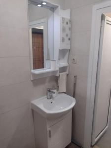 a white bathroom with a sink and a mirror at Сарафово Център in Burgas