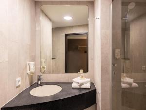 ein Bad mit einem Waschbecken und einem Spiegel in der Unterkunft B&B Hotel Essen in Essen