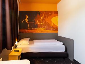 Schlafzimmer mit einem Bett mit Wandgemälde in der Unterkunft B&B Hotel Essen in Essen