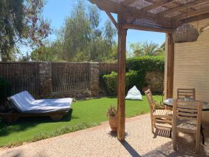 un giardino con pergolato, tavolo e sedie di Octopus Apartment - Lagoon Villa a Dahab