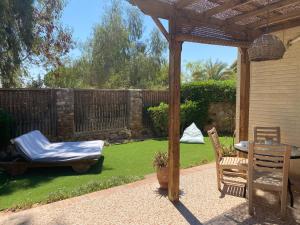 um jardim com uma pérgola, uma mesa e cadeiras em Octopus Apartment - Lagoon Villa em Dahab