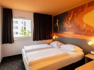 ein Hotelzimmer mit 2 Betten und einem Fenster in der Unterkunft B&B Hotel Essen in Essen