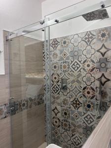 a bathroom with a shower with a tile wall at Longevity Hotel in Tortolì