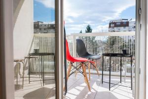 Un balcón con una silla roja y algunos taburetes en Skopje ELUXORY Apartments (Premium Edition), en Skopje
