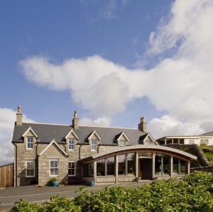 a large stone house with a large building at Mackay's Rooms in Durness