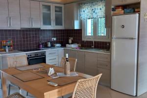 a kitchen with a table and a white refrigerator at The Ruby Cottage in Sami
