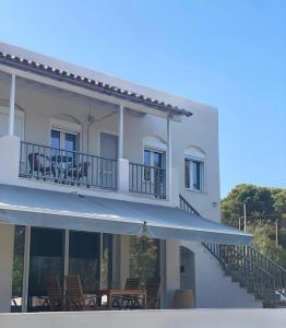 a white building with chairs and a balcony at Euphoria Estate in Agia Marina Aegina