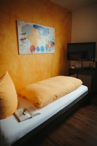 a bed with a yellow blanket and a book on it at Stadthotel Kleiner Berg in Friedrichshafen