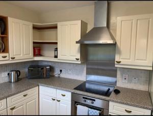 uma cozinha com armários brancos e um forno com placa de fogão em Stornoway Holiday Let em Stornoway