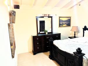 a bedroom with a bed with a dresser and a mirror at Sweet Holiday Haven in Ocho Rios