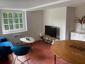 een woonkamer met een tafel en een televisie bij Gîte Normandie in Lisieux