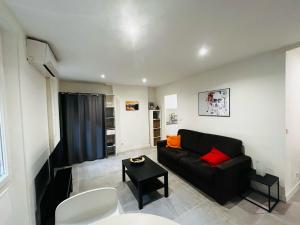 ein Wohnzimmer mit einem schwarzen Sofa und einem Tisch in der Unterkunft Le Paradis - Vieux Port, Studio avec climatisation in Marseille