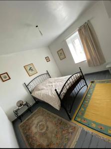 1 dormitorio con cama, ventana y alfombra en The Old School House, en Céaucé