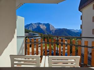 a balcony with two chairs and a view of mountains at Hostdomus - Oak Luxury Suite in Sestriere