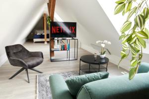 uma sala de estar com uma televisão e uma cadeira em Schlossberg Residences - XXL-Design-Apartment mit Schlossblick für bis zu 10 Personen em Schwetzingen