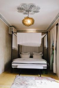 um quarto com uma cama de dossel e um lustre em Riad Maison 24 em Marrakech