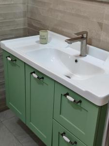 uma casa de banho com um lavatório verde e um balcão branco em זוהר במדבר ים המלח em Neve Zohar