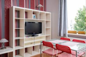 a living room with a tv and a table and chairs at Obrzeżna Standard Apartment in Warsaw