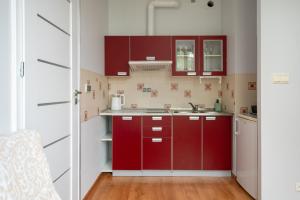 a kitchen with red cabinets and a sink at Obrzeżna Standard Apartment in Warsaw