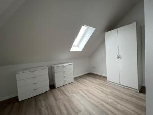 an attic bedroom with a skylight and white cabinets at Ferienwohnung Wicki in Kluse