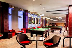 a billiard room with pool tables and red chairs at Pickalbatros White Beach Resort - Hurghada in Hurghada