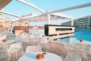 an outdoor patio with tables and chairs and a swimming pool at Pickalbatros White Beach Resort - Hurghada in Hurghada