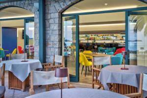 ein Restaurant mit Tischen und Stühlen und einer Steinmauer in der Unterkunft Hotel Villa Capri in Gardone Riviera + 22 Fotos