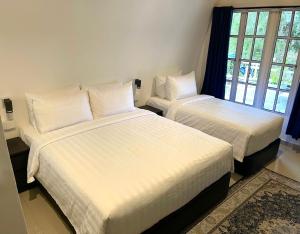 a bedroom with two beds with white sheets and a window at Blue Cabins By Pfordten Cottage in Cameron Highlands